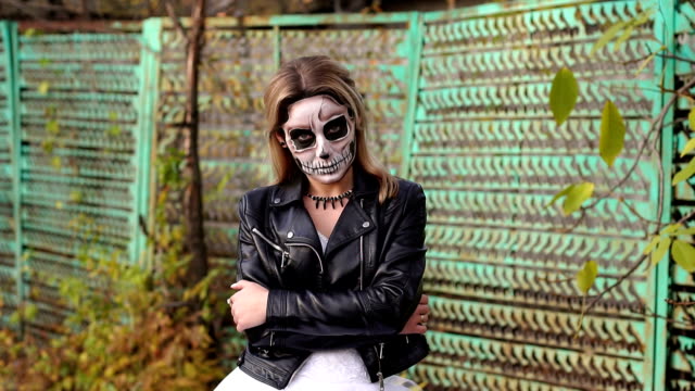 Creepy-bride-with-makeup-in-the-form-of-skull-on-the-background-of-an-old-fence.