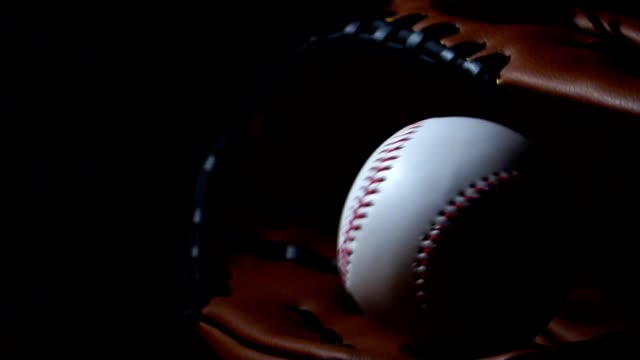 Werfen-Sie-einen-Baseball-mit-einem-Baseballhandschuh,-in-ein-dunkles-Licht-gelegt
