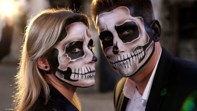 Couple-with-a-terrible-makeup-for-Halloween-stand-against-a-burning-fire.