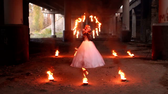 Creepy-bride-with-makeup-on-her-face-holding-burning-torches.-Halloween.