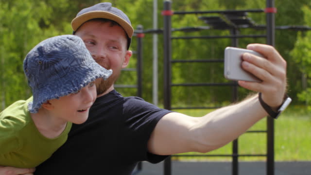 Kaukasischer-Vater-und-Sohn-machen-Selfies-im-Outdoor-Gym