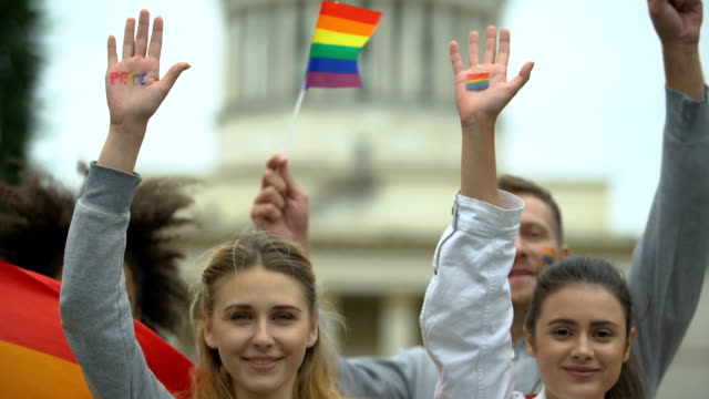 Aktivisten-springen-mit-LGBT-Parolen,-zeigen-bemalte-Regenbogensymbole,-Fahnen
