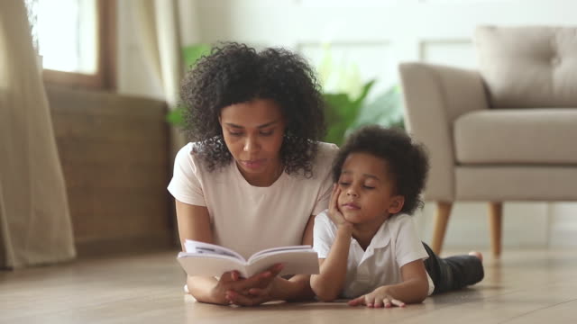 African-son-lying-on-floor-with-mother-reading-fairytale-story