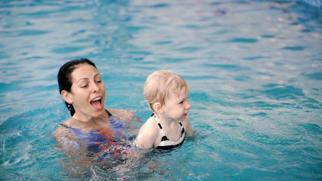 Schwimmbad.-Mama-bringt-einem-kleinen-Kind-das-Schwimmen-im-Pool-bei.