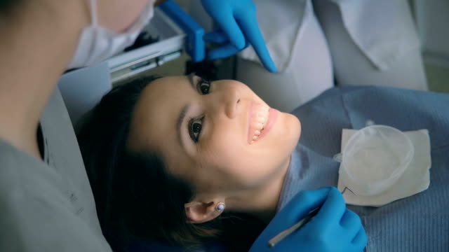 Junge-Frau-im-Zahnarztstuhl-sitzen-und-im-Gespräch-mit-dem-Arzt.-Weibliche-Lächeln-und-lachen-beim-Zahnarzt-Beratung