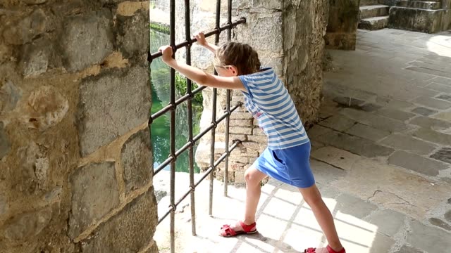 Young-girl-shake-grill-in-fortress-or-castle.-She-want-go-out.-Need-freedom.-Young-girl---prisoner-in-chateau.