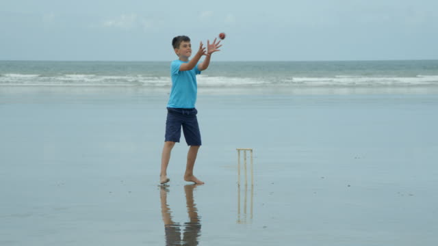 Un-niño-jugando-cricket-wicket-keeper-coge-la-bola-y-golpea-los-tocones.