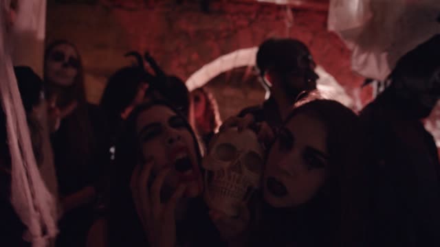 Mujeres-en-trajes-de-Halloween-góticos-sosteniendo-el-cráneo-en-fiesta-de-vestir