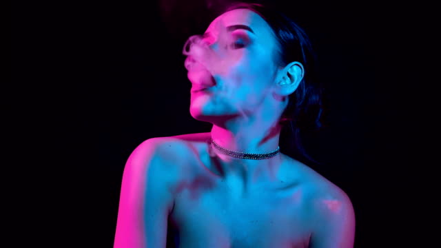 Wunderschöne-Brünette-Frau-rauchen-elektronische-Zigarette-in-Neon-Farbe-Licht