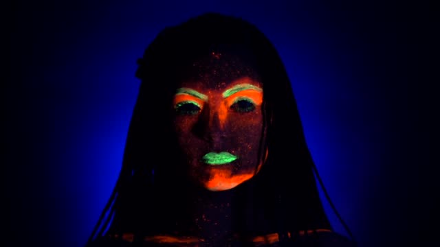 Fashion-model-woman-with-braids-in-neon-light.-Fluorescent-makeup-glowing-under-UV-black-light.-Night-club,-party,-halloween-psychedelic-concepts