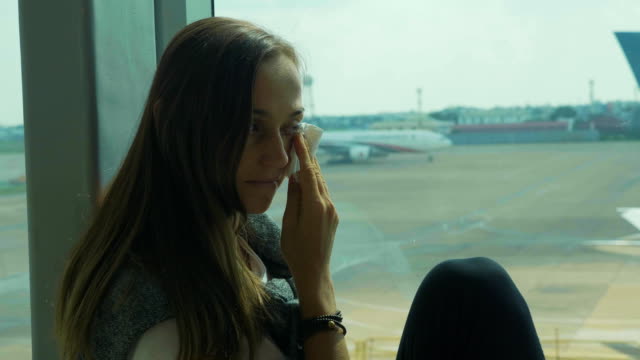 Young-sad-woman-is-crying-at-airport-with-airplane-on-the-background