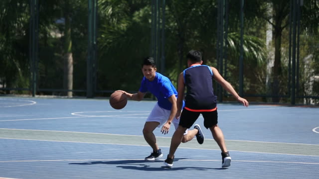 Junge-asiatische-Basketball-Spieler-spielen-auf-Freiplatz