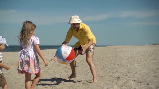 Vater,-spielen-Ball-mit-jungen-Geißlein-am-Strand-zu-genießen.-Familie-Sommer-Strandurlaub.-Slow-Motion.-Kinder-spielen-mit-Papa-am-Strand.