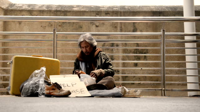 Die-Obdachlosen-werden-Pilz-vom-Brot-kratzen,-während-des-Wartens-auf-Spenden-von-Person-zu-Fuß-auf-dem-Bürgersteig.