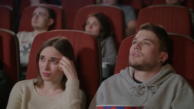 People-watching-scary-film-in-movie-theater.-Young-man-sprinkling-popcorn