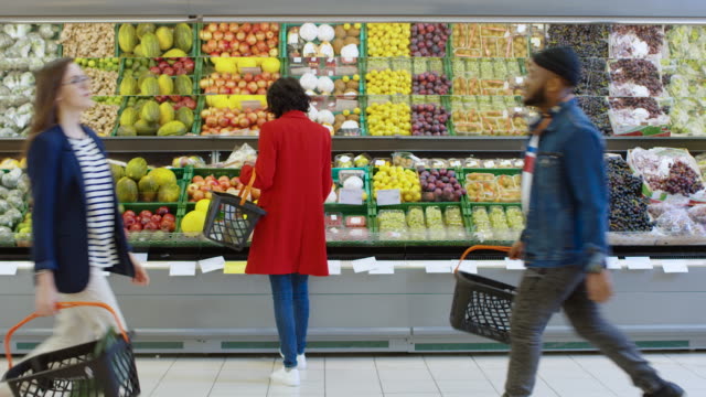 En-el-supermercado:-mujer-elige-producen-de-frutas-orgánicas-en-fresco-de-la-sección-de-la-tienda.-Ella-recoge-melón-y-pone-les-en-su-cesta-de-la-compra.-Vista-trasera-del-tiro.