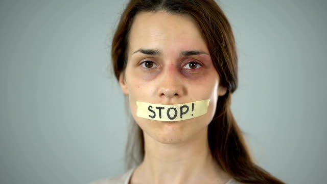 Stop-tape-on-lips-of-young-bruised-woman,-helpless-victim-of-violence-in-family