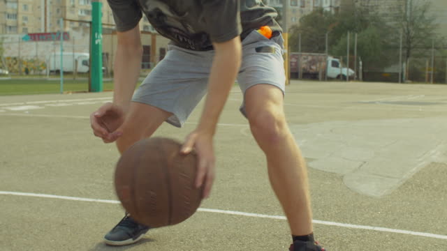 Männliche-Streetball-Spieler-Prellen-des-Balls-auf-Platz