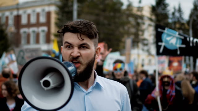 European-person-is-talking-in-megaphone-close-up.-People-scream-at-the-rally-4k.