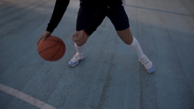 Female-basketball-player-in-shorts-and-white-socks-on-professional-court-running-with-ball-and-successfully-thowing-ball-to-the-net.-Handhelded-footage.-Outdoors