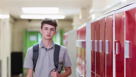 Portrait-Of-Male-High-School-Student-Walking-Down-Corridor-And-Smiling-At-Camera