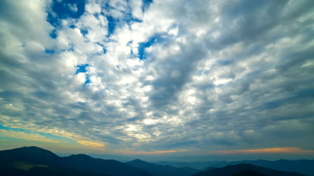 Die-schöne-Wolke-Stream-mit-einem-Sonnenuntergang-über-den-Bergen.-Zeitraffer