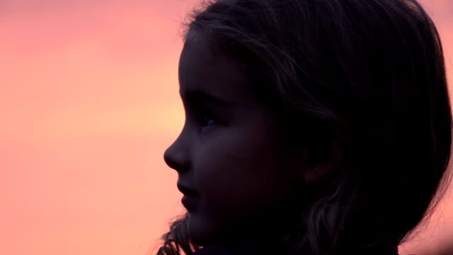 Kid-looking-up-at-the-sky-in-nature.-Little-girl-praying-looking-up-at-purple-sky-with-hope,-close-up.