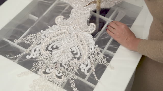 A-top-view-of-a-designer-cutting-out-the-sequined-and-beaded-lace-with-big-scissors-and-then-with-smaller-scissors