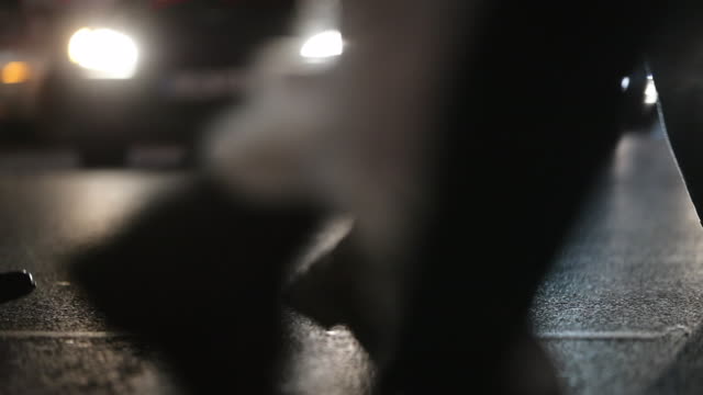 Unscharfe-abstrakte-Fußgänger-überqueren-der-Straße-in-der-Nacht-bei-120fps-slow-Motion.-Lens-Flares-von-Autos-im-Hintergrund-mit-Menschenmenge-im-Vordergrund