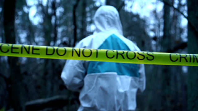 Victim's-clothing-at-crime-scene,-forensic-expert-collecting-evidence-in-forest