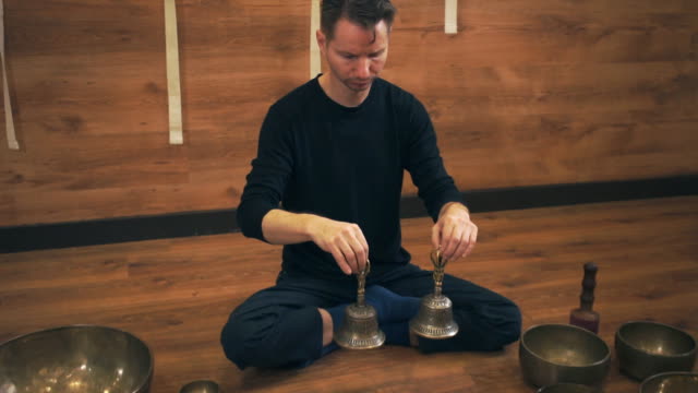 A-man-sits-near-the-Tibetan-singing-bowls-with-bells-in-their-hands