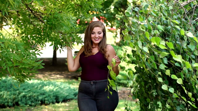 Ein-junges-Mädchen-mit-Übergewicht-geht-in-einem-Park-unter-grünen-Bäumen.
