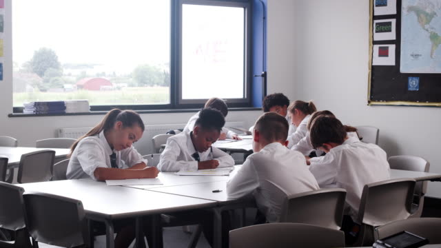 Grupo-de-estudiantes-de-secundaria-con-uniforme-trabajo-en-escritorio-en-el-aula