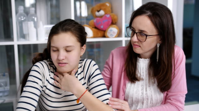 Advice-in-the-doctor's-office.-A-mother-and-daughter-a-teenager-on-the-medical-examination.-A-doctor-examines-a-sore-throat,-the-girl-of-the-patient.
