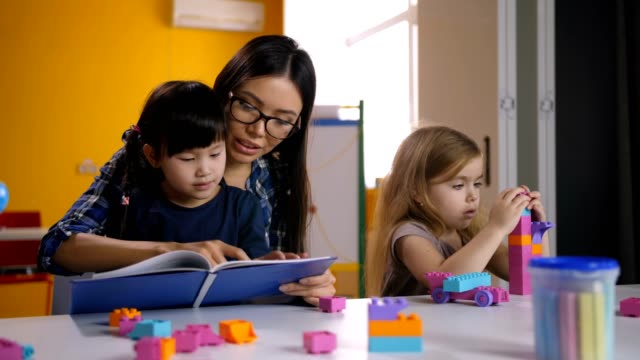 Teacher-and-kid-reading-book-in-kindergarten