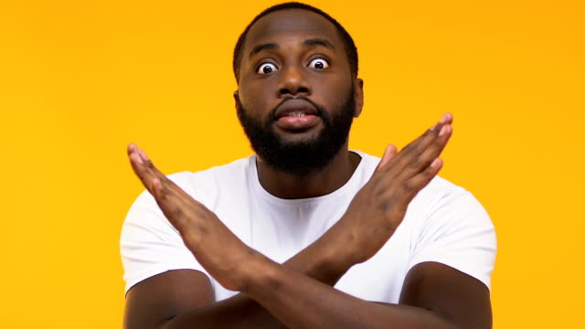 Emotionale-afroamerikanische-Männerkreuzung-Hände,-warnende-Geste,-gelber-Hintergrund
