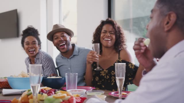 Familia-negra-de-múltiples-generaciones-sentada-en-la-mesa-de-la-cena-celebrando,-de-cerca-de-ángulo-bajo