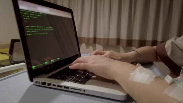 Patient-developer-coding-with-laptop-on-hospital-bed-during-sick