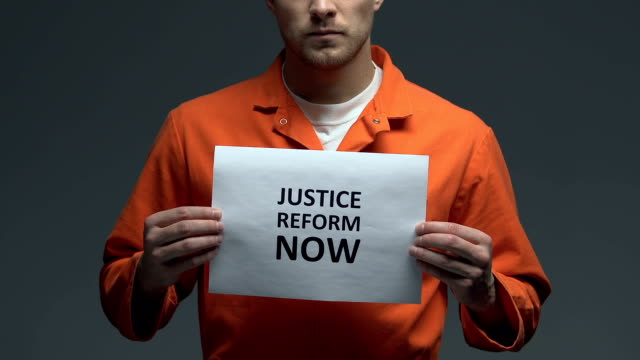 Justice-reform-now-demanding-on-card-in-hands-of-Caucasian-prisoner,-fairness