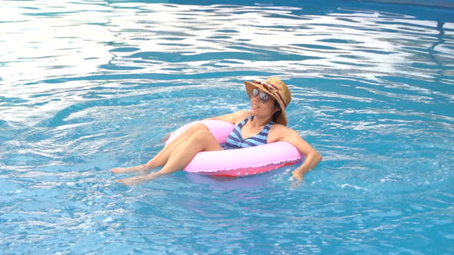 Girl-slow-motion-playing-and-swimming-on-ring-rubber-floating-on-swimming-pool