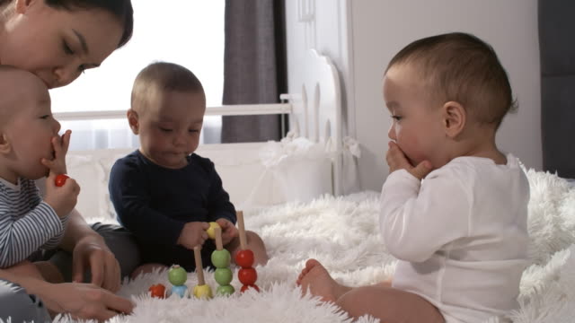 Teething-Asian-Triplets-Putting-Stacking-Toy-Beads-in-Mouth