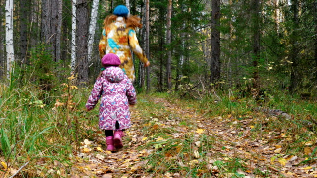 Mom-and-daughter-are-running-along-the-path-in-the-forest.