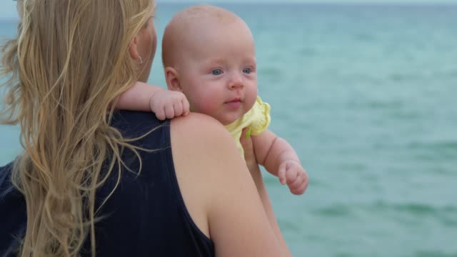 Mamá-con-hija-bebé-disfrutando-del-mar-y-la-brisa
