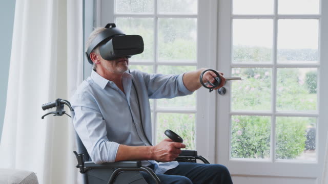 Hombre-discapacitado-senior-en-silla-de-ruedas-en-casa-usando-auriculares-de-realidad-virtual-sosteniendo-controladores-de-juego