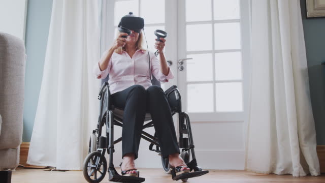 Reife-behinderte-Frau-im-Rollstuhl-zu-Hause-mit-Virtual-Reality-Headset-Gaming-Holding-Controller