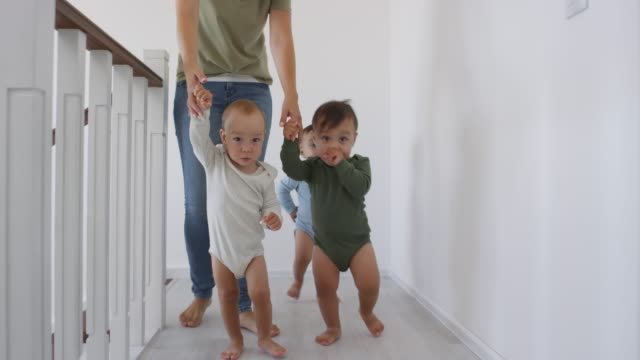 Unrecognizable-Woman-Leading-Asian-Baby-Triplets-by-Hand-at-Home