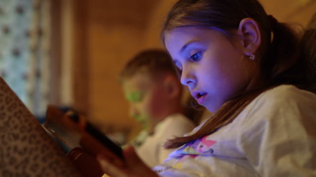 4K-kleine-Junge-und-Mädchen-sitzen-mit-Tablet-PCs-in-der-Hand-spielen-Videospiele