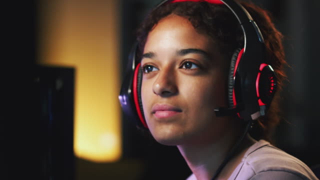Chica-adolescente-que-lleva-auriculares-jugando-en-línea-en-casa-con-amigos
