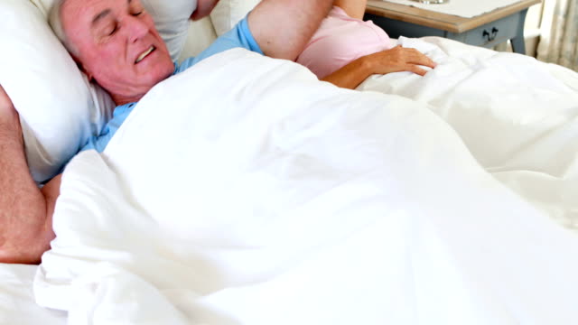 Senior-hombre-acostado-en-cama-y-cubriendo-sus-oídos-con-la-almohada