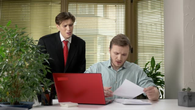 A-young-subordinate-employee-brought-the-boss-a-report,-a-document.-Makes-funny-faces-while-the-boss-does-not-see,-behind-his-back.-Work-in-the-office.-60-fps